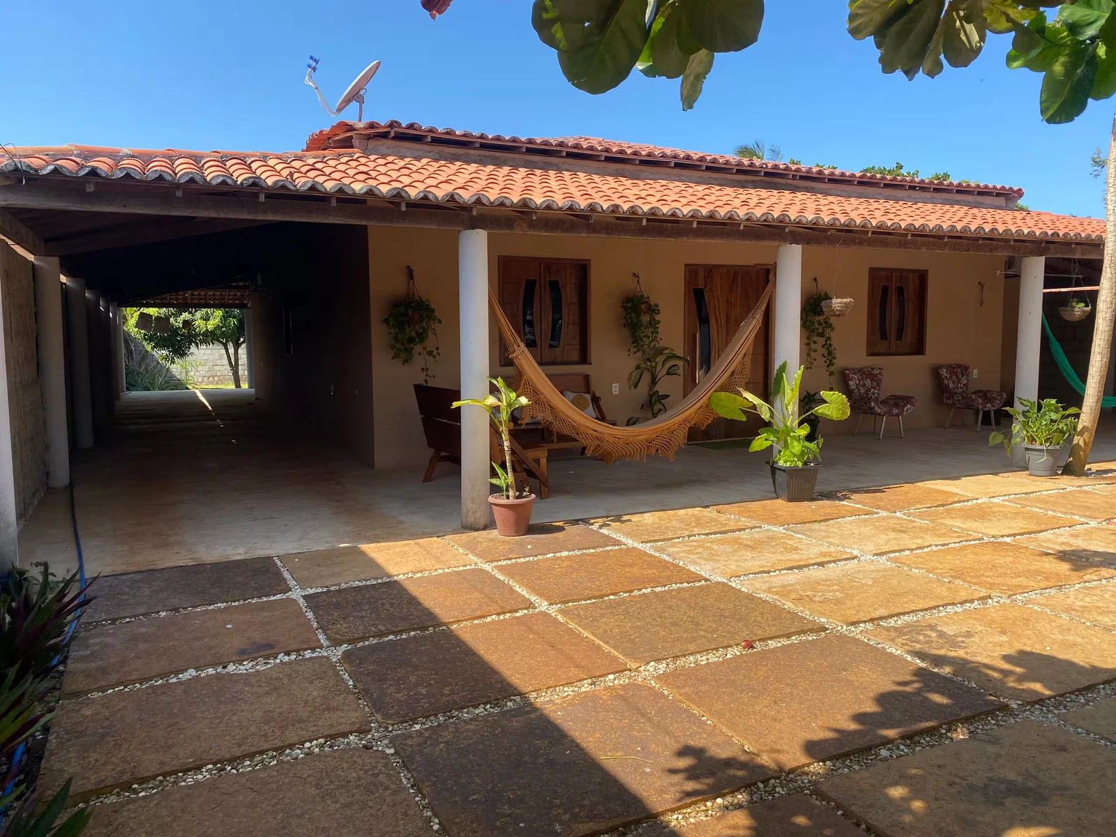 Frente de la casa con porche de tejado colonial y hamacas